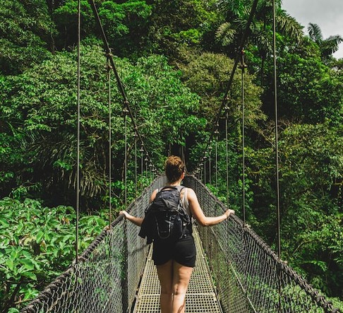 woman with backpack crossing a bridge during hiking 