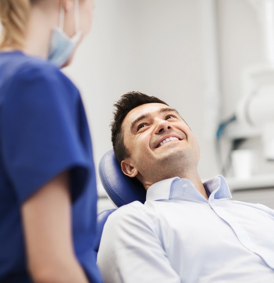 happy man sitting in dental office talking to female doctor